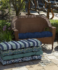 Weatherproof Outdoor Settee Cushion For Wicker Benches 41.5 By 18 Inches Fade Resistant Sapphire Blue UV Protected Outdoor Fabric PFAS Free Polyfill From Recycled Bottles Two Ties Fits Most Standard Outdoor Settees on wicker bench with greenery background