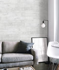 Peel And Stick Wall Panels For Kitchen Bedroom And Backsplash Dope Vinyl Planks With Strong Adhesive Vintage Farmhouse Wood Pattern In White With Grey Self Adhesive Flexible Tiles For Accent Walls And Doorways behind a grey couch.