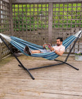 Man relaxing in Two Person Outdoor Hammock With Adjustable Metal Stand For Patio Or Garden, space saving Brazilian style, blue stripe