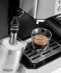 All In One Coffee And Espresso Maker With Dual Heating So You Can Brew Fast And Get Barista Grade Espresso 15 Bar Italian Pump Delivers Rich Flavor Adjustable Milk Frother For Creamy Cappuccinos And Lattes Glass 10 Cup Carafe COM532M Black close-up with milk frother and espresso cup