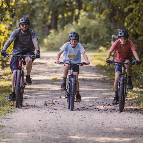 Flatrock DX Mountain Bike With 29 Inch Wheels 21 Speed Drivetrain Aluminum Frame Front Suspension Twist Shifters And Mechanical Disc Brakes Built Tough For Adult Men And Women On Rugged Trails on forest path with riders.