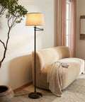 Caden LED Floor Lamp With Swing Arm Tall Bronze Standing Light beside a beige sofa in a living room setting