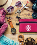 Swiss Safe pink 2-in-1 first aid kit pouch with logo on travel flat lay with camera and sunglasses