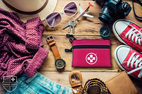 Swiss Safe pink 2-in-1 first aid kit pouch with logo on travel flat lay with camera and sunglasses