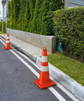 Row of heavy duty 28 inch traffic safety cones set of 6 with handles high visibility orange with reflective collars on a parking lot.