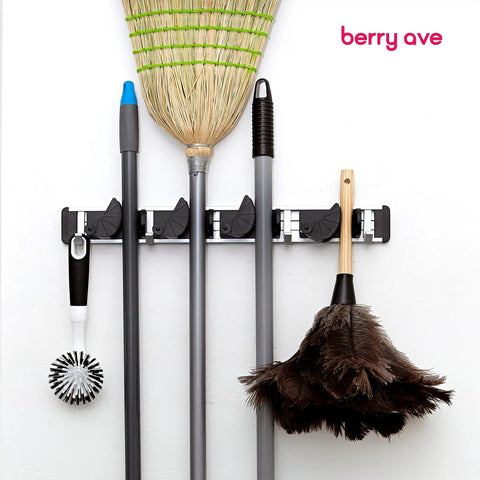 Beefy Heavy Duty Broom Wall Mount Organizer With Four Slots And Four Hooks For Brooms Mops Rakes And Garden Tools Holds Up To 1.25 Inches Handles Indoors Or Outdoors Storage For Kitchen Garage And Laundry Room holding cleaning tools.