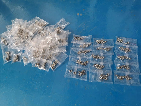 High Speed Auto Screw Packing And Counting Machine For Screw Kits, Pro Packaging System with filled sachets on blue surface