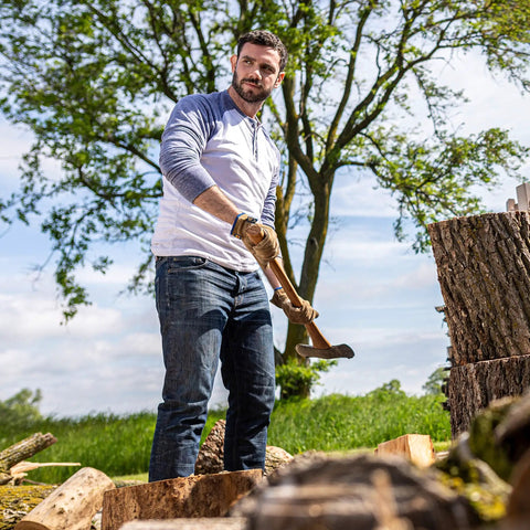 Man chopping wood wearing HydraHyde Leather Work Gloves For Ranching, Fencing And Construction, Water Resistant Split Cowhide.