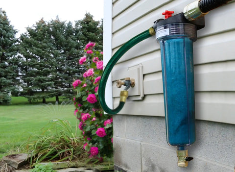 HydroFeed 32-Ounce In-Line Auto-Mix Fertilizer Injector System for Drip Irrigation installed on an exterior wall with a garden hose.