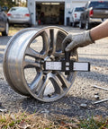Universal Wheel Bolt Pattern Gauge For 4 5 6 8 Lug Wheels measuring a wheel on a gravel surface, highlighting dual scale readings.