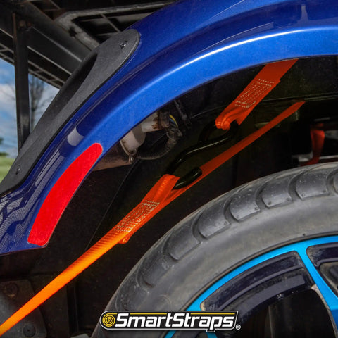Blue vehicle secured with SmartStraps 14Ft Premium Ratchet Strap Set 4 Pack For Hauling Heavy Loads With 3000 Lbs Break Strength And 1000 Lbs SWL.