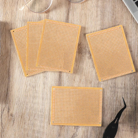 Top view of 5 brown 70mm x 90mm PCB boards from 10 Pack 70mm x 90mm PCB Board Prototype Kit Universal Printed Circuit Board Copper Stripboard Perfboard For Electronics Experiments And DIY Soldering Projects Perfect For Makers And DIYers on a wooden table.