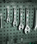 Set of adjustable wrenches hanging on a pegboard, including 10 Inch Adjustable Wrench With 1-7/16 Inch Jaw Opening Chrome Vanadium Steel Rust Resistant.