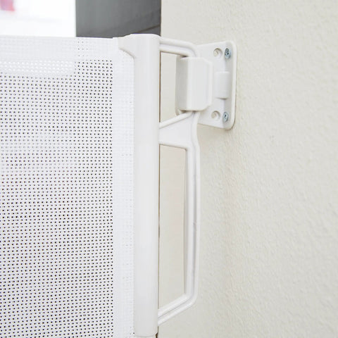 Close-up of retractable indoor outdoor pet safety gate shown with detachable mount on a wall, highlighting no trip hazards
