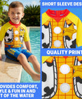Boy wearing Two Piece Toy Story Boys Rash Guard And Swim Trunks Set With Woody And Buzz Lightyear Graphics by the poolside.