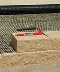 Versa-Lok Versa Lifter Standard Tool For Easy And Safe Handling Of Block Walls on concrete blocks and mesh background.