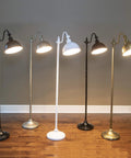 Sweet Matte Black Steel Pharmacy Floor Lamp Featuring Matching Metal Shade And Easy Rotary Switch Ideal For Brightening Up Your Living Room Office Or Cozy Reading Nook With Vintage Meets Modern Vibes displayed with other colored lamps on wooden floor.