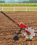 Manual Garden Push Seeder With 7 Nozzles And Eight Pound Seed Box Easy To Use Depth Settings One To Three Inches For Corn Soybean Peanut Roller Seeding Machine For Small Farms And Vegetable Fields Red in field.