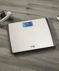 Digital Bathroom Scale 550 Pound Capacity With Extra Wide 15 Inch By 13 Inch Platform Stainless Steel Body on wood floor