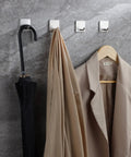 Self Adhesive Towel Hooks Four Pack Stick On Wall Stainless Steel 304 No Drill Bathroom Kitchen Hooks For Keys Robes And Towels Holds Up To 21 Pounds Heavy Duty Adhesive holding umbrella, towel, and coat on stone wall
