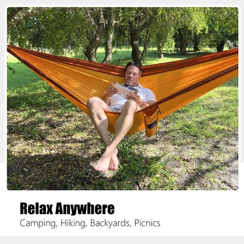Person relaxing in an orange Double Camping Hammock With Tree Hanging Kit And 12Kn Aluminum Wiregate Carabiner Parachute Nylon.