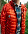 Hex Peel And Stick Repair Patches Kit applied on orange down jacket outdoors, hexagonal patch visible on left side.