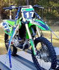 Adjustable Motorbike Fork Stand Heavy Duty Dirt Bike Transport Rack stabilizing a dirt bike in a trailer with blue tie-down straps.