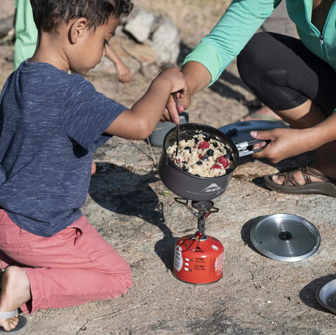 Family cooking with Go To Solo Camping Pot 1.3 Liter With Nonstick Ceramic Fusion Coating on a portable stove outdoors.