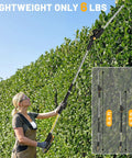 Person using Cordless Pole Hedge Trimmer With 14-Foot Reach And 18-Inch Cutting Head, compatible with 20V Max batteries, in garden.