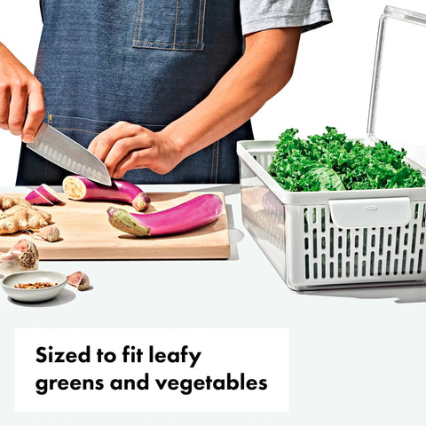 Person chopping vegetables near Produce Saver Bin With Adjustable Divider For Fresh Produce Storage In Fridge Medium White BPA Free