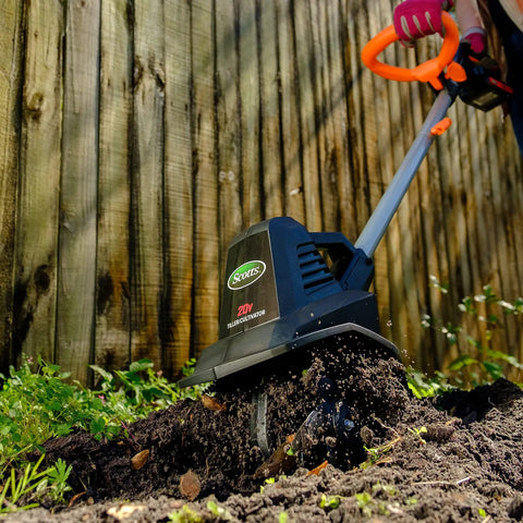 20V Cordless Garden Tiller Cultivator with 7.5 Inch Width in use, tilling soil near wooden fence, highlighting steel tines