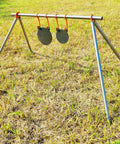 AR500 Steel Target Gong Silhouette For Precision Shooting, Half Inch Thick, on a metal frame in grassy field