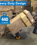 Beefy Folding Dolly With Aluminum Frame, 440 LB Capacity Hand Truck with rugged rubber wheels moving boxes in a warehouse.