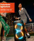 Stage 320 Portable Party Speaker With Telescopic Handle And Wide Wheels For Dope Portable Vibes Pro Sound Futuristic Light Show Up To 18 Hours Of Play Time Splash Proof Built For Outdoor Parties And Big Rooms on a rooftop with people dancing.