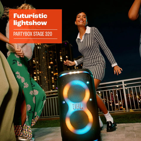 Stage 320 Portable Party Speaker With Telescopic Handle And Wide Wheels For Dope Portable Vibes Pro Sound Futuristic Light Show Up To 18 Hours Of Play Time Splash Proof Built For Outdoor Parties And Big Rooms on a rooftop with people dancing.