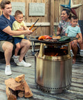 Family gathered around Bonfire Hub Stainless Steel Cooking Adapter For 8 Inch Elevation Fire Pit with food on grill.