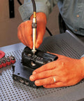 Person using Big League Air Scribe Engraving Pen With Rolling Throttle And 13500 Blows Per Minute on black metal part for marking.
