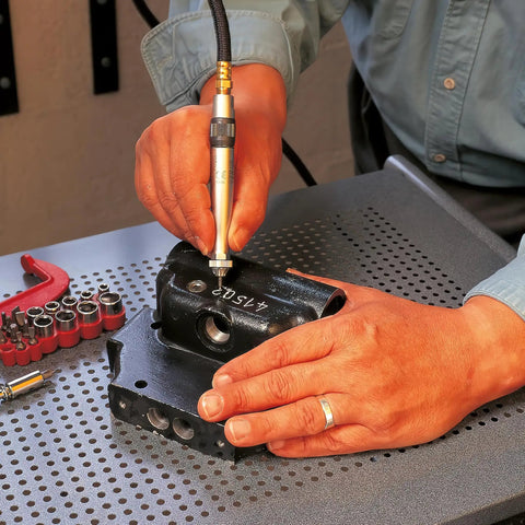 Person using Big League Air Scribe Engraving Pen With Rolling Throttle And 13500 Blows Per Minute on black metal part for marking.