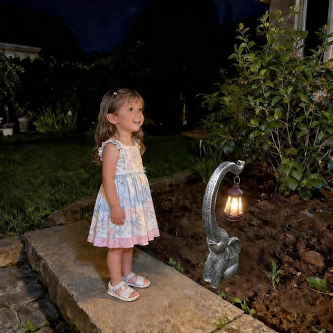 Child admiring Outdoor Solar Powered Elephant Garden Statue With LED Lantern Lights illuminating a garden path at night.