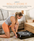 Woman storing Rumblex 4D Vibration Plate Exercise Machine with triple motor under a couch.