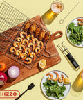 Top view of stainless steel Shallow Grill Basket Set for outdoor grilling with shrimp, vegetables, skewers, and basting brush on table.