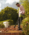 Person using 18V One Plus Brushless Compact Blower Bare Tool With Variable Speed Trigger And Lock On for yard cleanup on steps.
