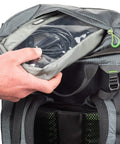 Hand accessing cable pouch in Rotating 50L Plus Camera Backpack For Epic Adventure Photography With Front Access, Tripod Carry.