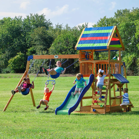 Children playing on Beachfront Cedar Wood Swing Set With Wave Slide Elevated Deck Canopy Monkey Bars Rock Wall Ladder Shaded Picnic Area Snack Bar Window Belt Swings Trapeze Sandbox Playset For Kids in a backyard