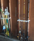 Easy Clip Garage Door Storage Rack with hooks securing fishing rods and garden tools, installed on garage door hinge tubes.
