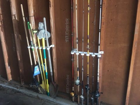 Easy Clip Garage Door Storage Rack with hooks securing fishing rods and garden tools, installed on garage door hinge tubes.
