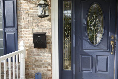 Locking Wall-Mounted Mailbox in Rubbed Bronze next to a blue door, Galvanized Steel Outdoor Mailbox with Secure Drop Box