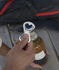 Using Dual Bottle Opener And SBiner Carabiner Combo In Stainless Steel on a beer bottle outdoors