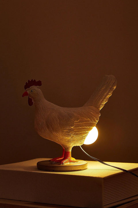 Lit 3D Lifelike Chicken Egg Lamp Night Light, emitting a warm glow, resin egg table lamp placed on a bedside table with USB.