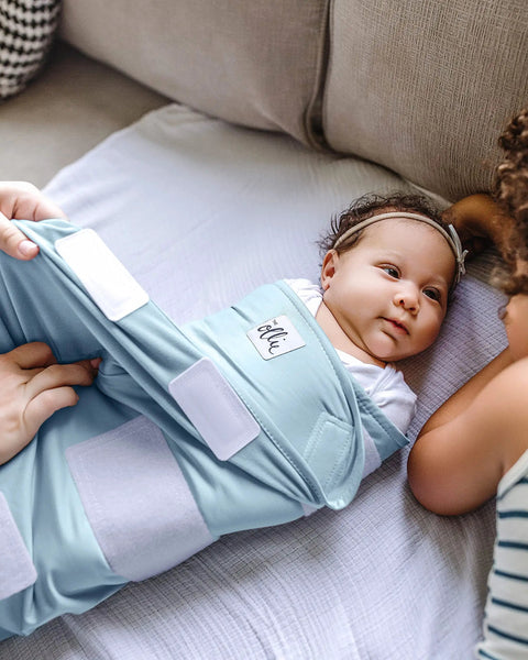 Newborn in sky blue Adjustable Baby Swaddle For Newborns That Feels Like The Womb Pediatrician Recommended Safe Sleep Solution.